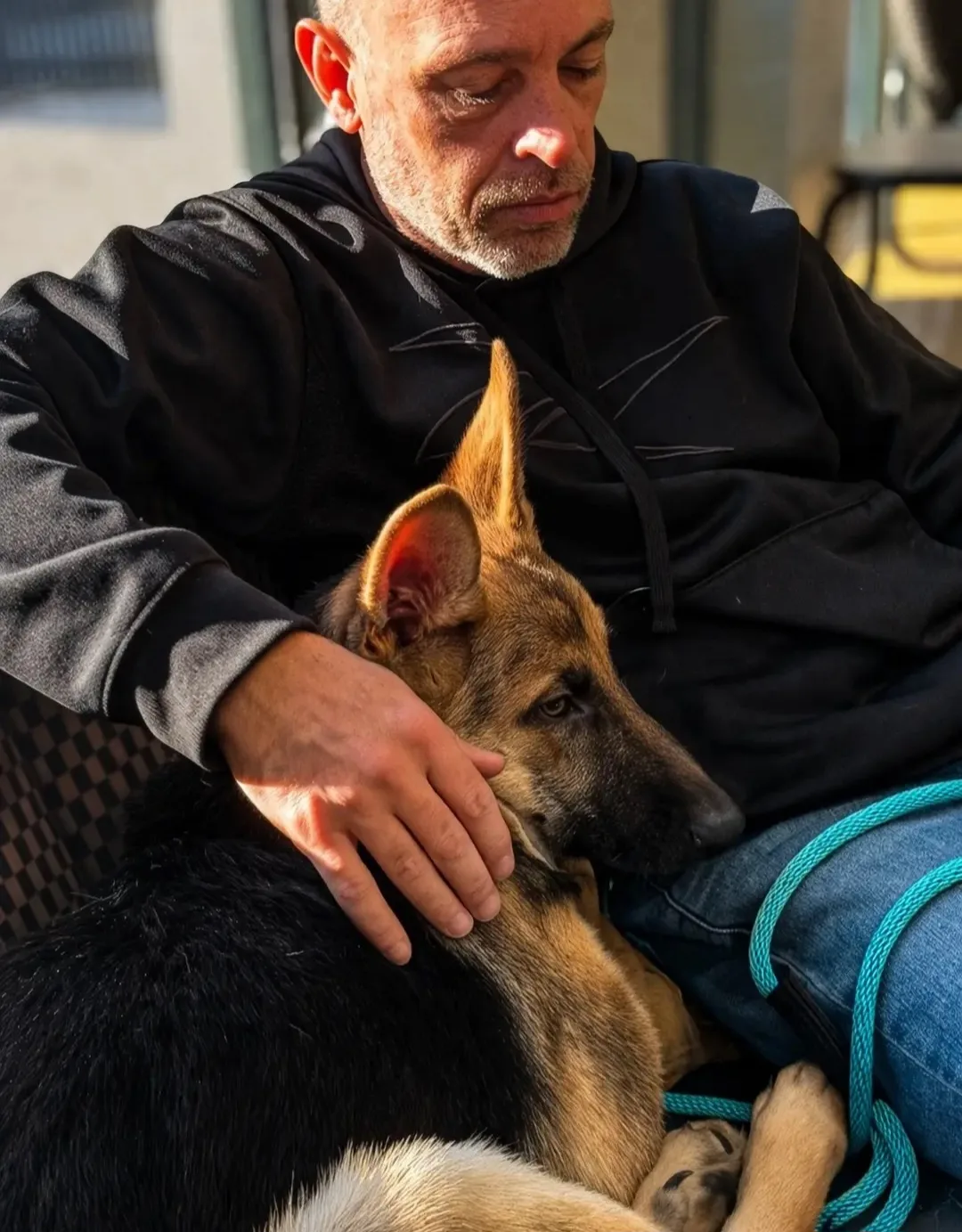 Steve the Dogman sitting with a German Shepherd puppy resting against him