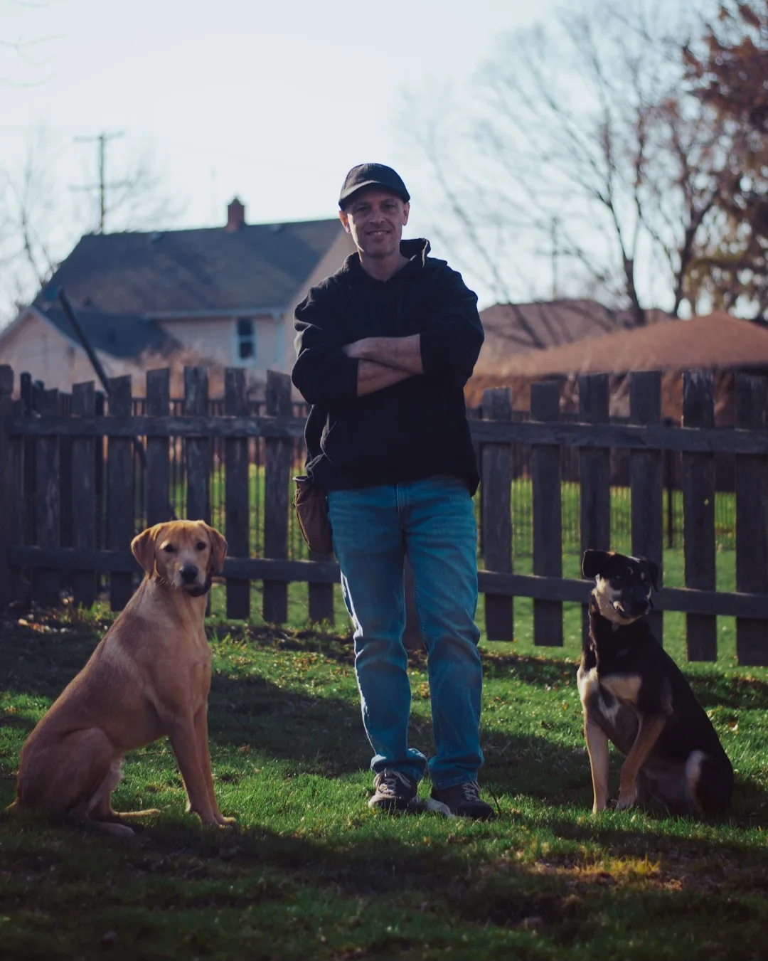 Steve the Dogman standing with two dogs holding a sit either side of him